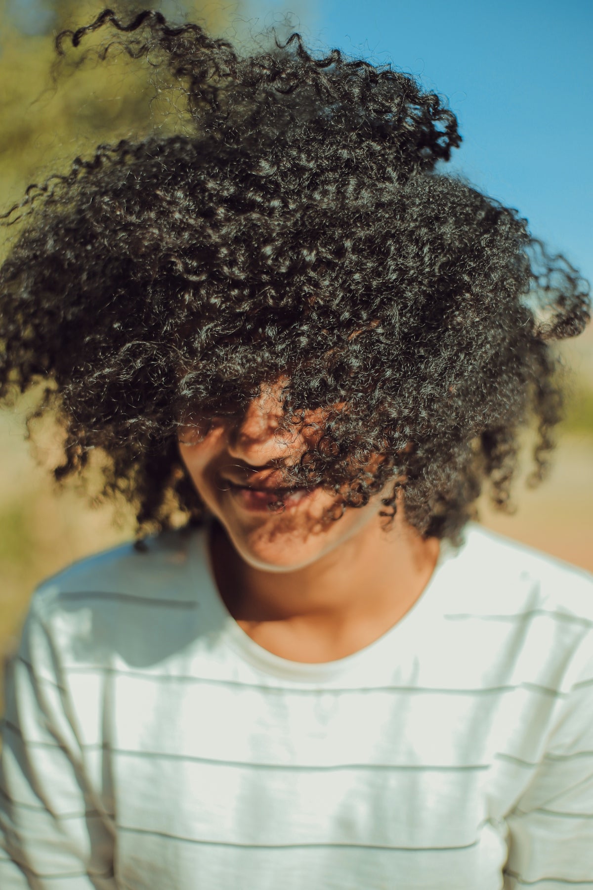 person wearing white crew-neck shirt with curly hair photo Image
