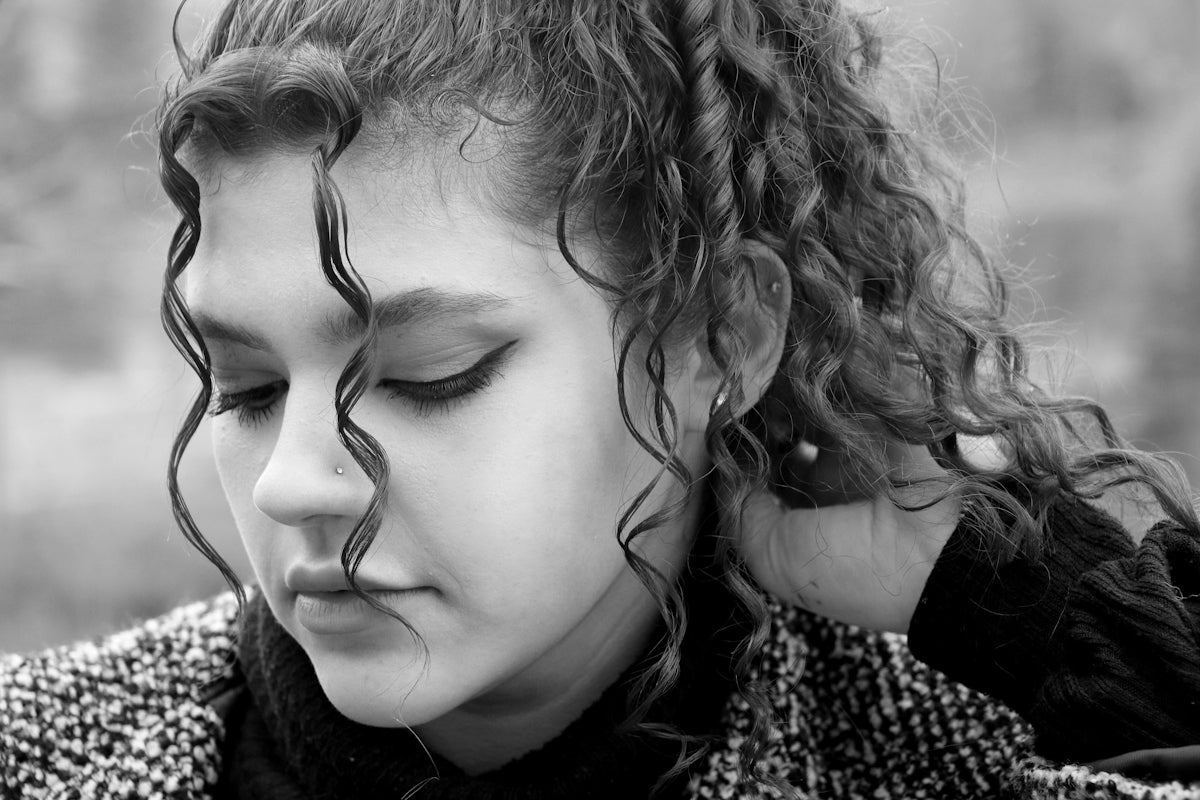 A woman with curly hair is looking down at her cell phone